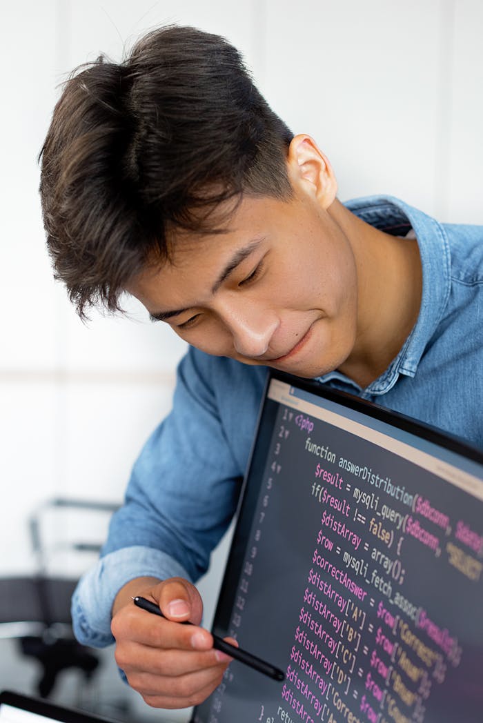 services-03 A young man smiles while programming in a modern office environment.